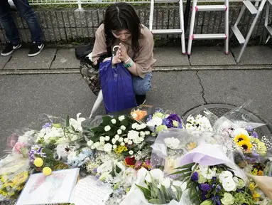 Seorang wanita berdoa untuk para korban kebakaran  di gedung Kyoto Animation Studio di Kyoto, Jepang (19/7/2019). Korban tewas kebakaran di studio animasi di Kyoto, Jepang bertambah menjadi 33 orang. Motif pembakaran yang disengaja ini masih diselidiki otoritas setempat. (AP Photo/Jae C. Hong)