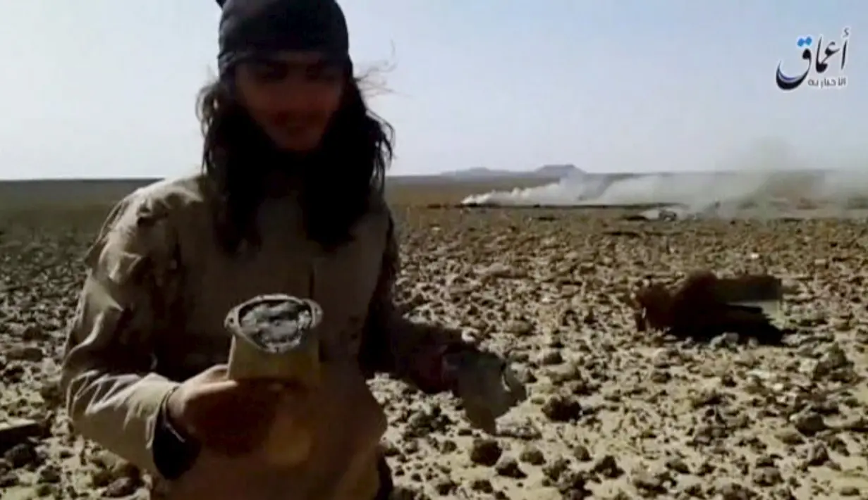 Seorang pria berpose didekat bangkai pesawat yang jatuh dan terbakar di sebelah tenggara Damaskus, Jumat, (22/4). ISIS juga mengaku telah menangkap pilot pesawat itu setelah terjun dengan parasut. (Reuters)