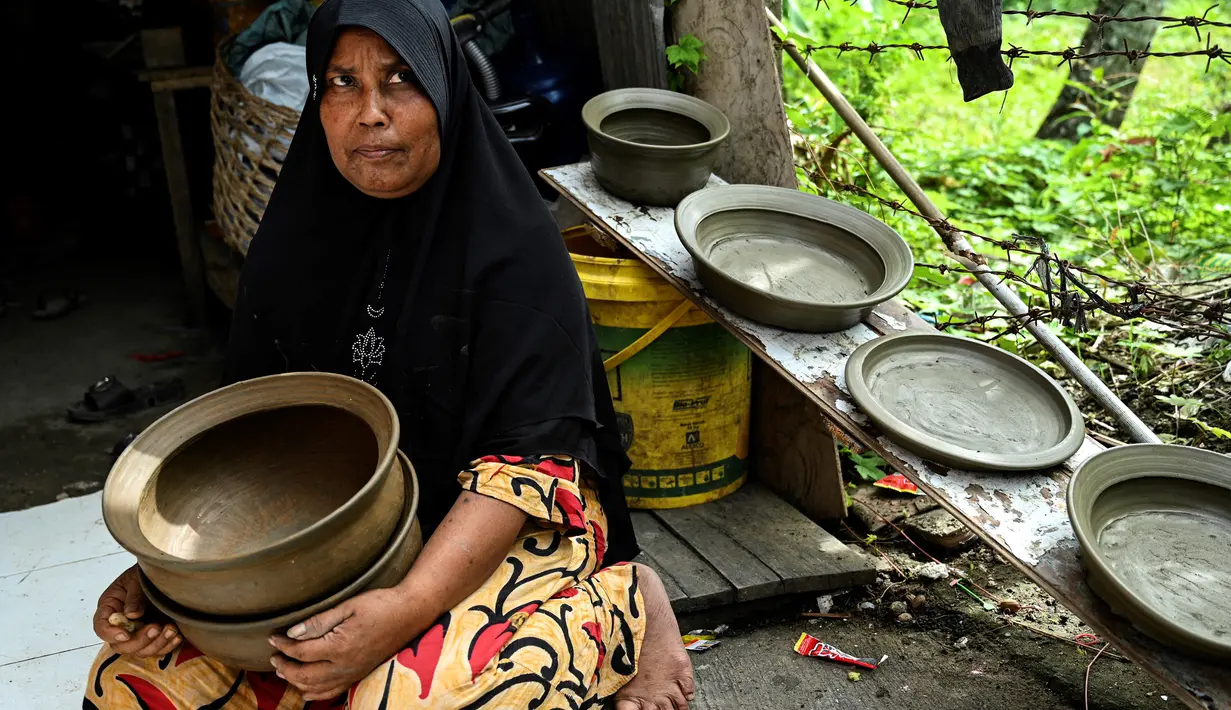 Seorang pembuat tembikar memegang pot tanah liat buatannya dalam bengkel rumah di Banda Aceh, Aceh, Rabu (4/8/2021). (CHAIDEER MAHYUDDIN/AFP)