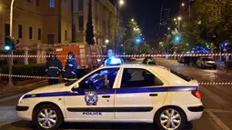 Polisi mengamankan lokasi ledakan bom yang menghantam sebuah kantor bank Eurobank di pusat kota Athena, Yunani, Rabu (19/4). Berdasarkan laporan, perangkat peledak itu ditempatkan di sebuah tas yang diletakan dekat pintu masuk bank (LOUISA GOULIAMAKI/AFP)