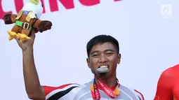 Atlet ParaCycling, Sufyan Saori menggigit medali perak nomor Mens C5 Individual Time Trial Road Race Asian Para Games 2018 di Sirkuit Sentul, Bogor, Senin (8/10). Sufyan Saori berhasil merebut medali perak. (Liputan6.com/Helmi Fithriansyah)