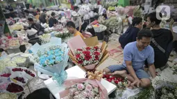 Perajin menata buket atau karangan bunga di Pasar Bunga Rawa Belong, Jakarta, Senin (14/2/2022). Perajin buket setempat mengaku permintaan pesanan karangan bunga yang biasa dihadiahkan saat hari kasih sayang atau Valentine Day tersebut menurun. (Liputan6.com/Faizal Fanani)