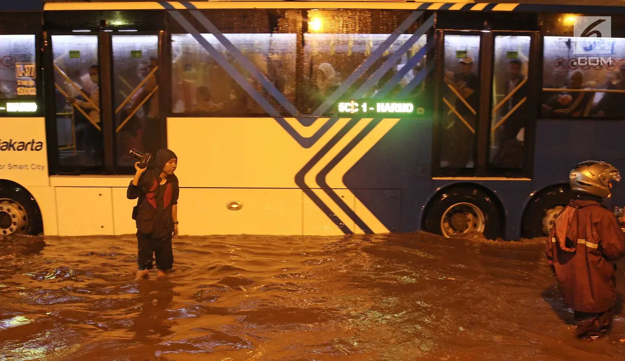 Bus Transjakarta menerobos banjir di terowongan (underpass) Cawang, Jalan MT Haryono, Jakarta, Selasa (12/12). Hujan deras dan buruknya drainase di kawasan tersebut menjadi penyebab utama adanya genangan air hingga 50 cm. (Liputan6.com/Herman Zakharia)