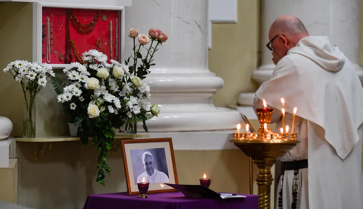 Ekspresi seorang anggota rohaniwan di depan potret Paus Fransiskus di salah satu Gereja Katolik, Saint Petersburg pada Senin (21/4/2025). (Olga MALTSEVA/AFP)
