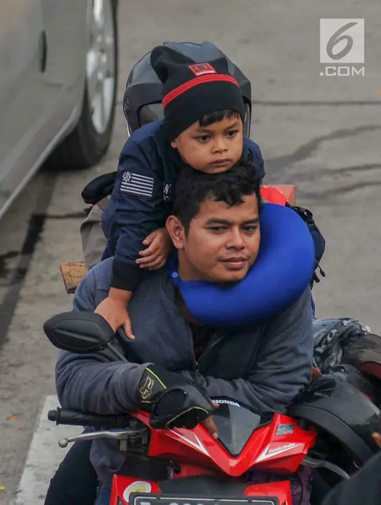 Pemudik menggendong anak sambil menanti waktu masuk kapal penyebrangan di Dermaga 1 Pelabuhan Penyebrangan Merak, Banten, Sabtu (1/6/2019). Meski berbahaya, pemudik tetap nekat membawa anak berkendara sepeda motor menuju kampong halaman. (Liputan6.com/Helmi Fithriansyah)