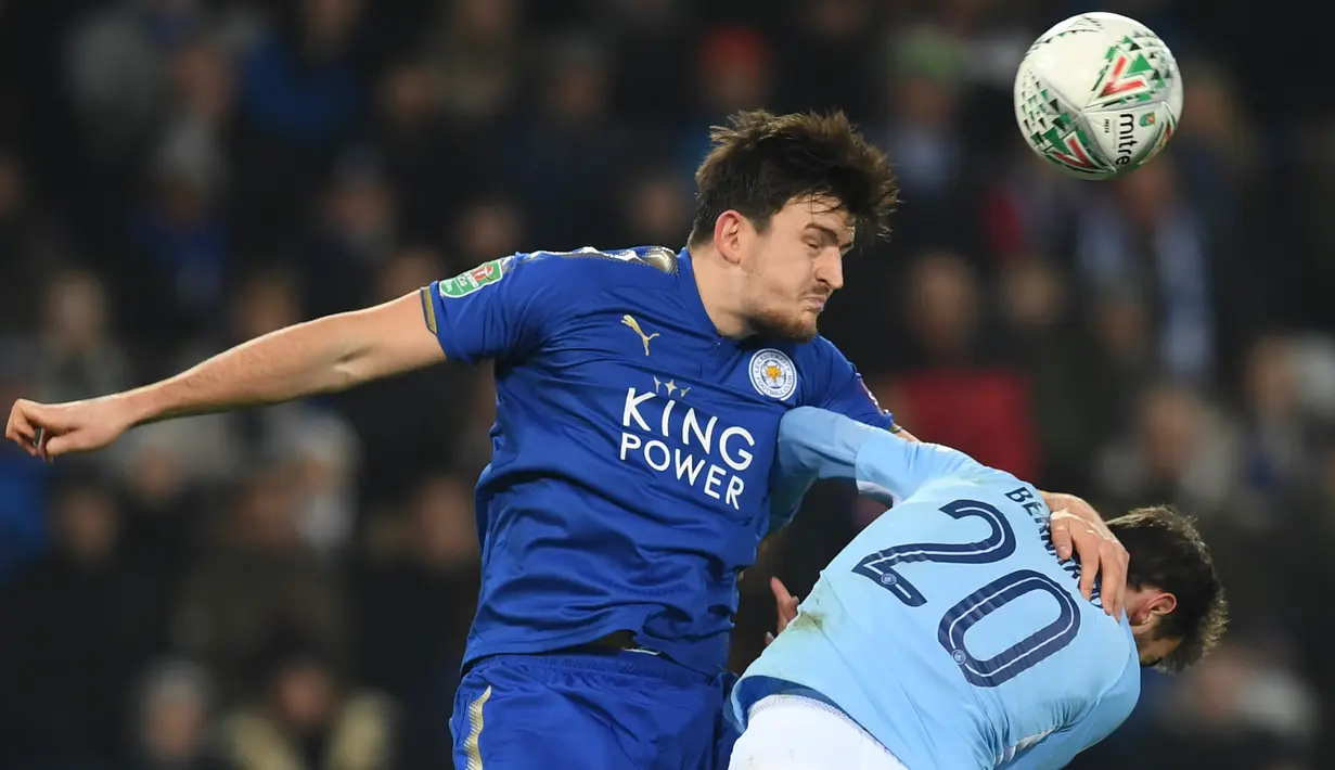 Bek Leicester City Harry Maguire berebut bola dengan gelandang Manchester City, Bernardo Silva pada perempat final Piala Liga Inggris di King Power Stadium, Selasa (19/12). Manchester City melaju ke semifinal usai menang dengan skor 4-3. (Paul ELLIS/AFP)