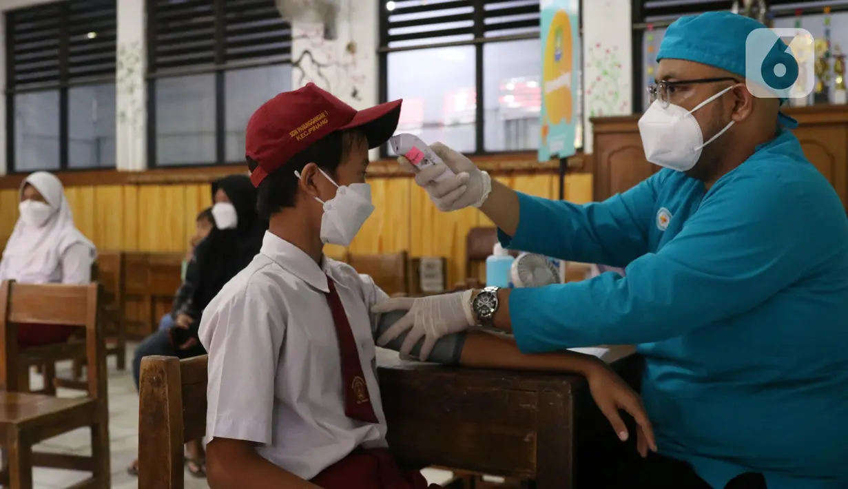 Petugas mengukur suhu seorang siswa sebelum mengikuti vaksinasi covid-19 di SDN Panunggangan 5, Pinang, Kota Tangerang, Selasa (19/10/2021).  Pelaksanaan vaksinasi untuk pelajar usia 12 tahun ini dilakukan dalam rangka persiapan pelaksanaan pembelajaran tatap muka (PTM). (Liputan6.com/Angga Yuniar)