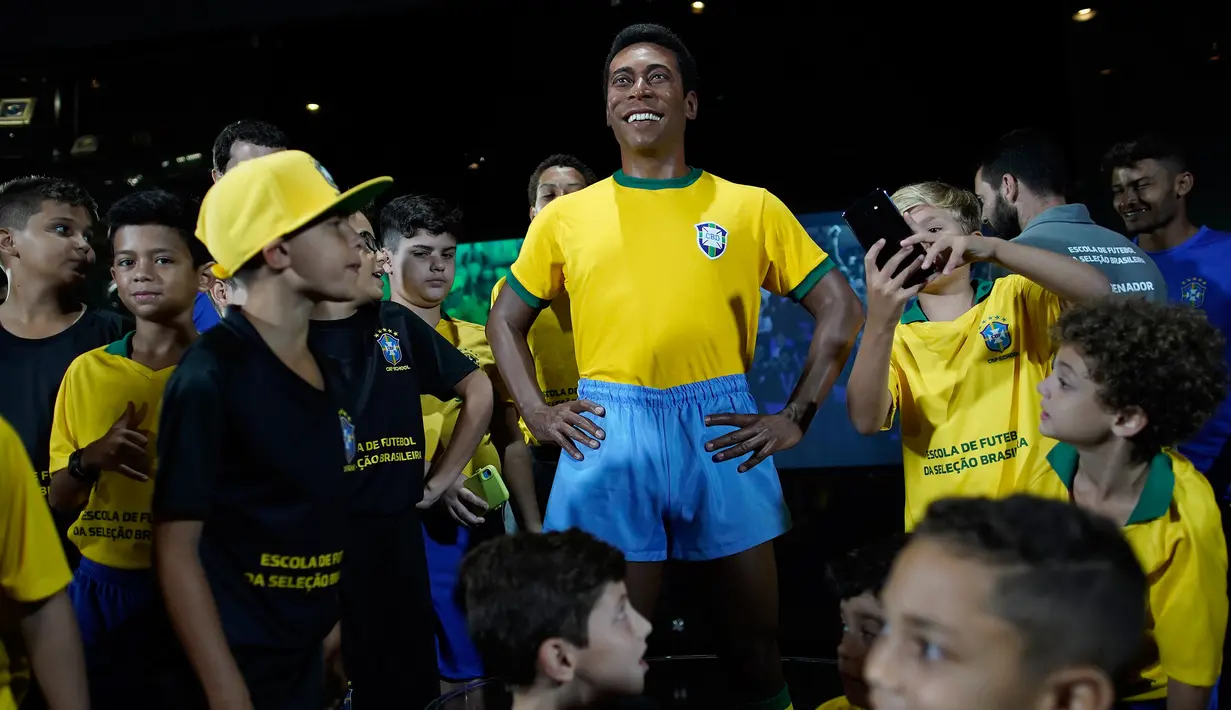 Anak-anak berdiri dekat  patung pemain sepak bola legendaris Brasil, Pele, di Museum Tim Sepak Bola Brasil di Rio de Janeiro, Kamis (20/2/2020). Konfederasi Sepak Bola Brasil meluncurkan patung Pele sebagai bagian dari peringatan 50 tahun sejak kemenangan Piala Dunia 1970. (AP/Leo Correa)