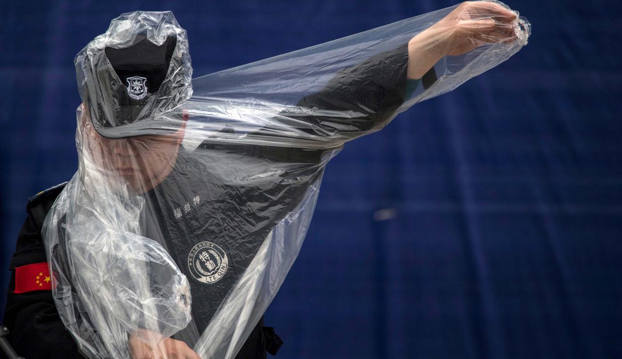 Seorang petugas kemanan mencoba mengenakan jaket hujan saat berjaga pada sesi latihan bebas F1 GP China di Shanghai, (6/4/2017). (AFP/Johannes Eisele)