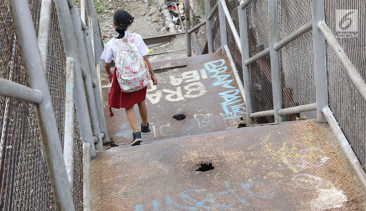 Seorang anak menuruni tangga di JPO di kawasan Tebet, Jakarta, Selasa (6/3). Kondisi JPO yang memprihatinkan menyebabkan sebagian warga lebih memilih untuk tidak menggunakannya karena membahayakan keselamatan. (Liputan6.com/Immanuel Antonius)