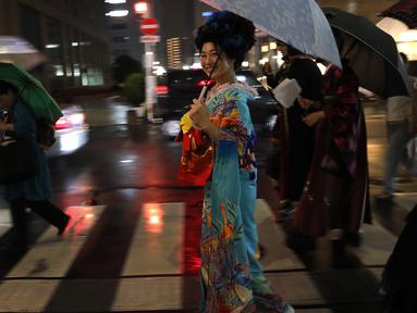 Seorang wanita Jepang tersenyum mengenakan pakaian tradisional saat berjalan di jalan setelah menghadiri peragaan busana kimono di Oita (18/10/2019). Pada zaman sekarang, kimono berbentuk seperti huruf "T", mirip mantel berlengan panjang dan berkerah. (AP Photo/Christophe Ena)