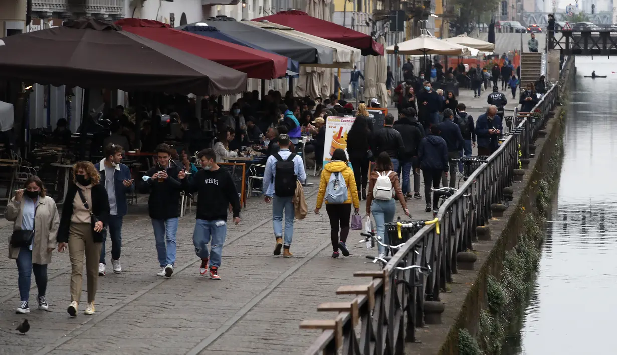 Orang-orang berjalan di sepanjang kanal di distrik Naviglio di Milan, Senin (26/4/2021). Italia kembali dibuka secara bertahap pada hari Senin setelah enam bulan memberlakukan lockdown untuk menghambat penyebaran corona Covid-19. (AP Photo/Antonio Calanni)