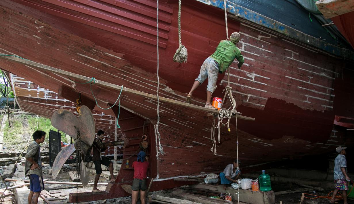 Para pekerja saat memperbaiki sebuah kapal di galangan kapal di tepi Sungai Yangon, yang terletak di pinggiran Yangon, Myanmar (30/7/2019). (AFP Phot/Sai Aung Main)