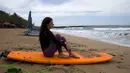 Seorang turis Rusia duduk di papan selancarnya saat menyaksikan ombak di Pantai Kuta, Bali, Jumat (4/2/2022). Bali kembali dibuka untuk pelancong asing dari semua negara setelah penerbangan internasional dilanjutkan untuk pertama kalinya dalam dua tahun. (AP Photo/Firdia Lisnawati)