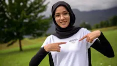 Atlet sepeda jalan dari tim pengungsi Afghanistan Masomah Ali Zada tersenyum saat berpose dengan kausnya yang dihiasi Cincin Olimpiade di World Cycling Center (CMC) di Aigle (1/7/2021). Masomah Ali Zada akan berkompetisi di Olimpiade Tokyo 2020. (AFP/Fabrice Coffrini)