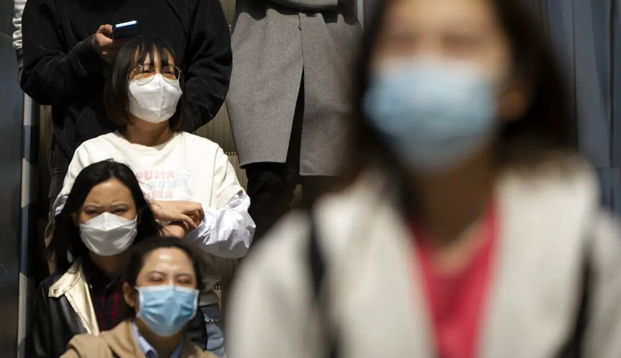 Orang-orang yang mengenakan masker naik eskalator di kompleks perbelanjaan dan perkantoran di Beijing, China, 13 April 2022. Shanghai bergerak untuk lebih melonggarkan lockdown di kota terbesar di China tersebut yang tampaknya terhenti. (AP Photo/Mark Schiefelbein)