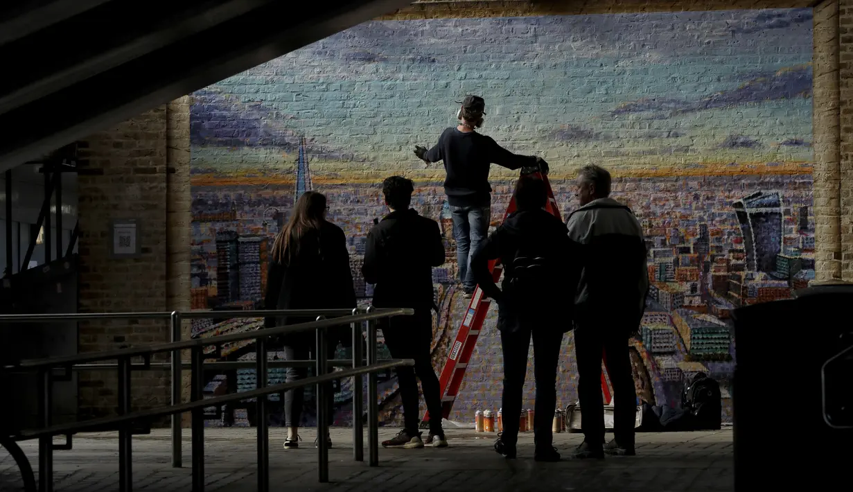 Orang-orang berhenti untuk menyaksikan seniman jalanan Australia James Cochran, juga dikenal sebagai Jimmy C, memberikan sentuhan akhir pada mural lanskap kota London-nya di dinding Network Rail oleh Blackfriars Station, di London (5/10/2020). (AP Photo/Matt Dunham)