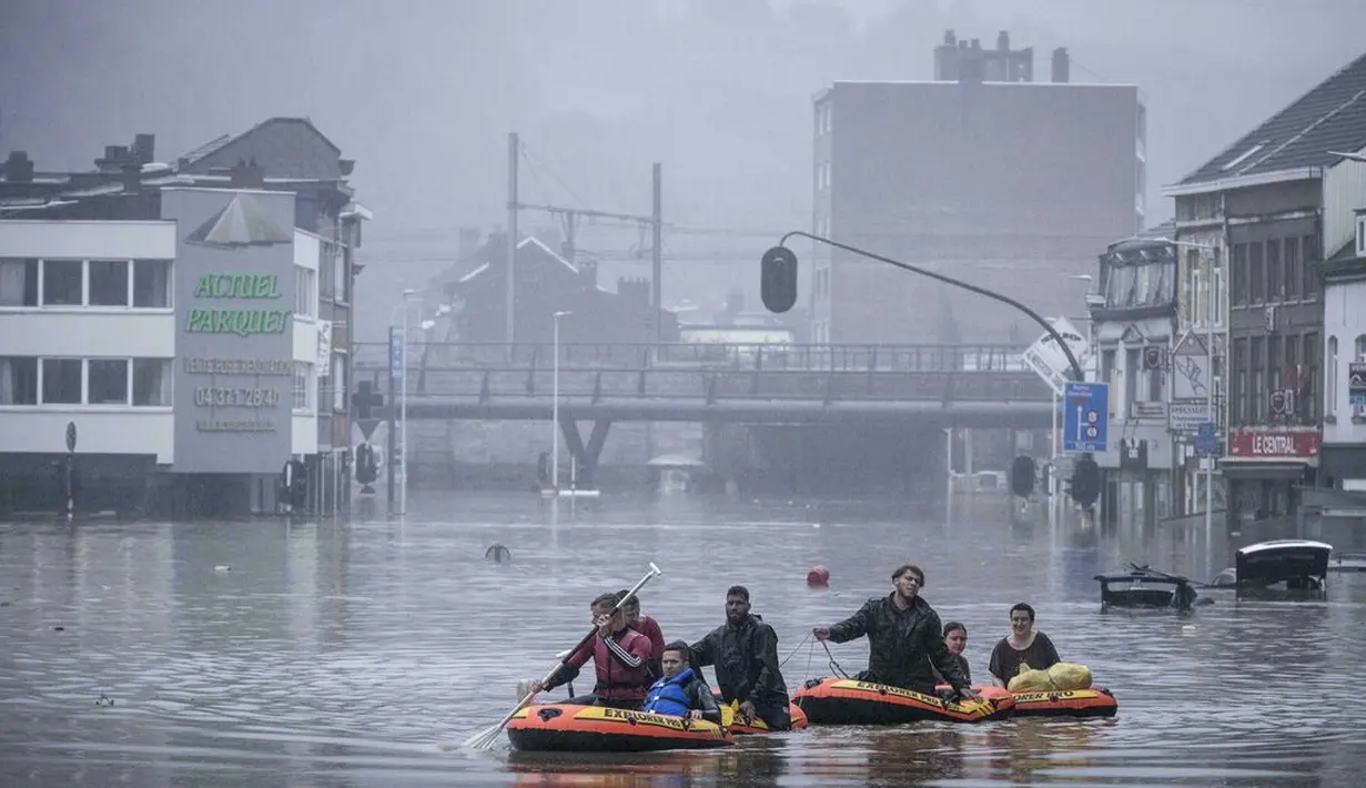 Warga menggunakan rakit karet di tengah banjir setelah Sungai Meuse jebol saat banjir besar di Liege, Belgia, Kamis (15/7/2021). Hujan lebat dan banjir telah menewaskan sedikitnya 59 orang di Jerman dan sembilan di Belgia. (AP Photo/Valentin Bianchi)