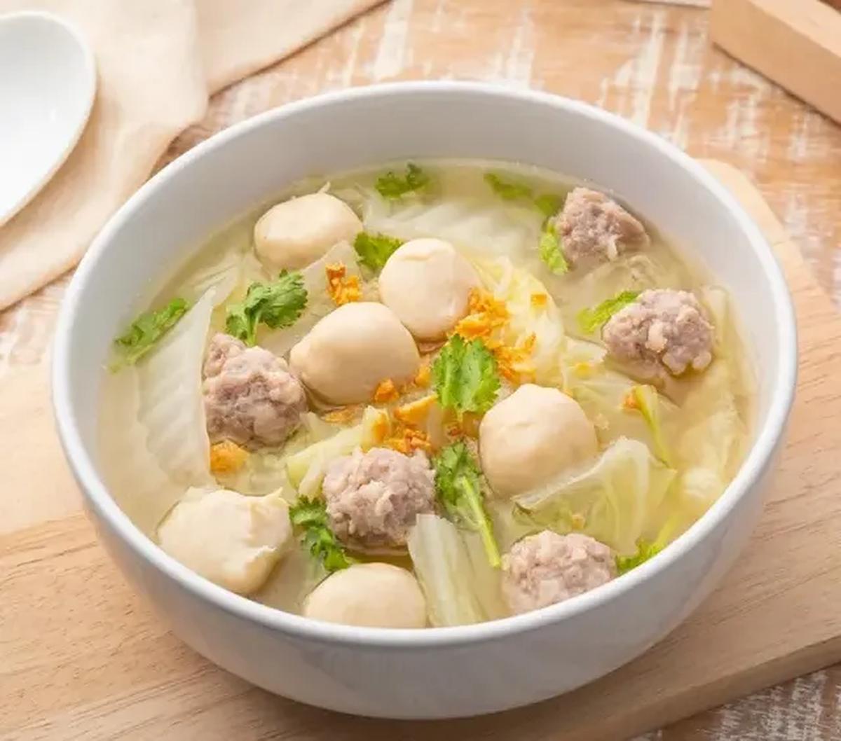 Suami Yenny dengan cekatan menyiapkan meja, panci elektrik, setumpuk mangkung kertas, dan untuk beberapa bahan pelengkap bakso.