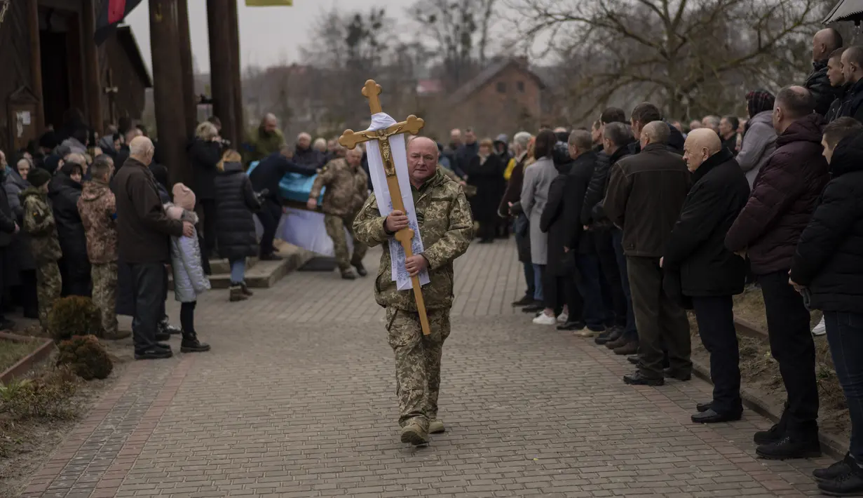 Orang-orang menghadiri upacara pemakaman prajurit militer Ukraina Roman Rak dan Mykola Mykytiuk di Starychi, Ukraina barat, Rabu (16/3/2022). Rak dan Mykytiu tewas dalam serangan rudal Rusia hari Minggu di sebuah pangkalan pelatihan militer di Yavoriv. (AP Photo/Bernat Armangue)