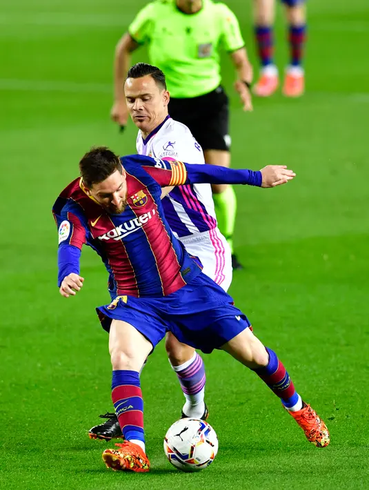 Gelandang Real Valladolid, Roque Mesa (tengah) menantang penyerang Barcelona, Lionel Messi pada pekan ke-29 Liga Spanyol di Camp Nou, Selasa (6/4/2021) dini hari WIB. Barcelona susah payah menang tipis 1-0 berkat gol Ousmane Dembele. (Pau BARRENA/AFP)