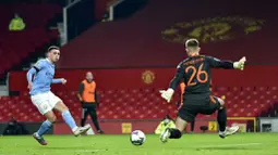 Pemain Manchester City, Phil Foden, melepaskan tendangan ke gawang Manchester United pada laga Piala Liga Inggris di Stadion Old Trafford, Rabu (6/1/2021). City menang dengan skor 2-0. (Peter Powell/Pool via AP)