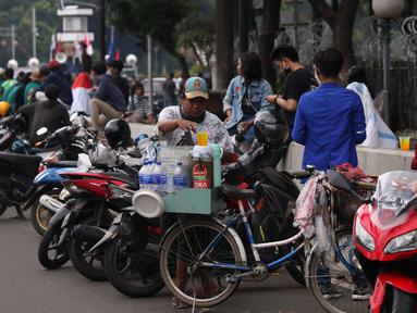 Pedangang membuat minuman untuk massa aksi saat demo penolakan omnibus law di kawasan Patung Kuda, Jakarta, Selasa (20/10/2020). Para pedagang kaki lima memanfaatkan moment aksi massa untuk mencari ke untungan meskipun sangat membahayakan bagi keselamatan mereka. (Liputan6.com/Angga Yuniar)