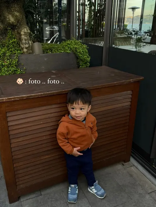 Sadar outfitnya keren, Baby Issa meminta sang ibu memotret outfitnya. Mengenakan sweater oranye dan jogger pants navy [@nikitawillyofficial94]