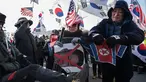 Pengunjuk rasa anti-Korea Utara merobek bendera Korea Utara saat melakukan aksi menyambut kedatangan kapal feri Korea Utara yang membawa rombongan seni untuk tampil di Olimpiade Musim Dingin Pyeongchang 2018, Korea Selatan (6/2). (AFP/Ed Jones)