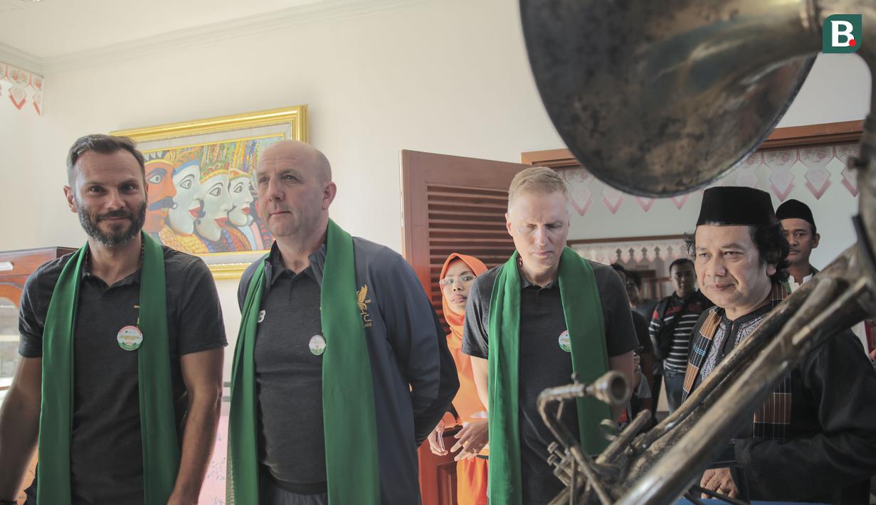 Legenda Liverpool, Patrik Berger dan Gary McAllister disambut dan diiringi saat memasuki rumah adat Betawi dalam rangkaian acara kunjungan budaya di Kawasan Perkampungan Betawi Setu Babakan, Jakarta (9/9/2018). (Bola.com/Peksi Cahyo)