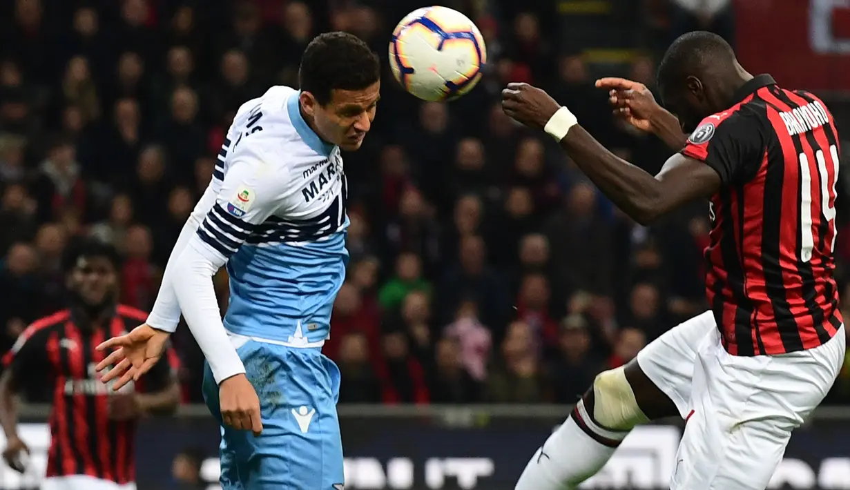 Bek Lazio, Luiz Felipe berebut bola udara dengan gelandang AC Milan, Tiemoue Bakayoko selama pertandingan lanjutan Liga Serie A Italia di stadion San Siro (13/4). Milan menang tipis atas Lazio 1-0. (AFP Photo/Miguel Medina)