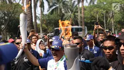 Pelari membawa obor Asian Games 2018 dalam Torch Relay Asian Games 2018 di kawasan TMII, Jakarta, Rabu (15/8). Pada Jumat (17/8), kirab obor berlanjut di wilayah Kab Administrasi Kepulauan Seribu, lalu ke Monas dan Istana. (Liputan6.com/Immanuel Antonius)