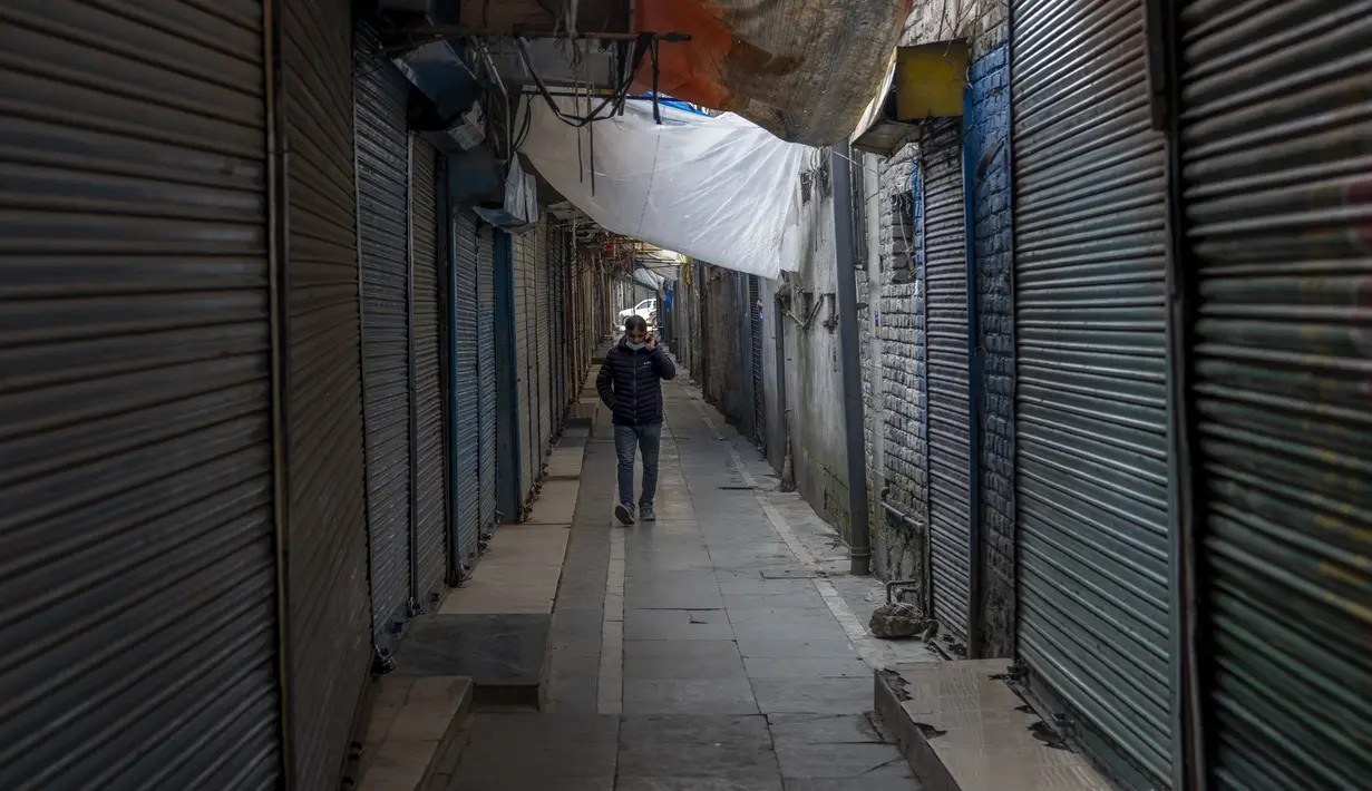Pria Kashmir berjalan di luar pasar tertutup di Srinagar, Kashmir yang dikuasai India, Sabtu (15/1/2022). Pihak berwenang di bagian Kashmir India mengumumkan pembatasan penuh pergerakan yang tidak penting selama akhir pekan di seluruh negara bagian untuk mengekang COVID-19. (AP Photo/Dar Yasin)