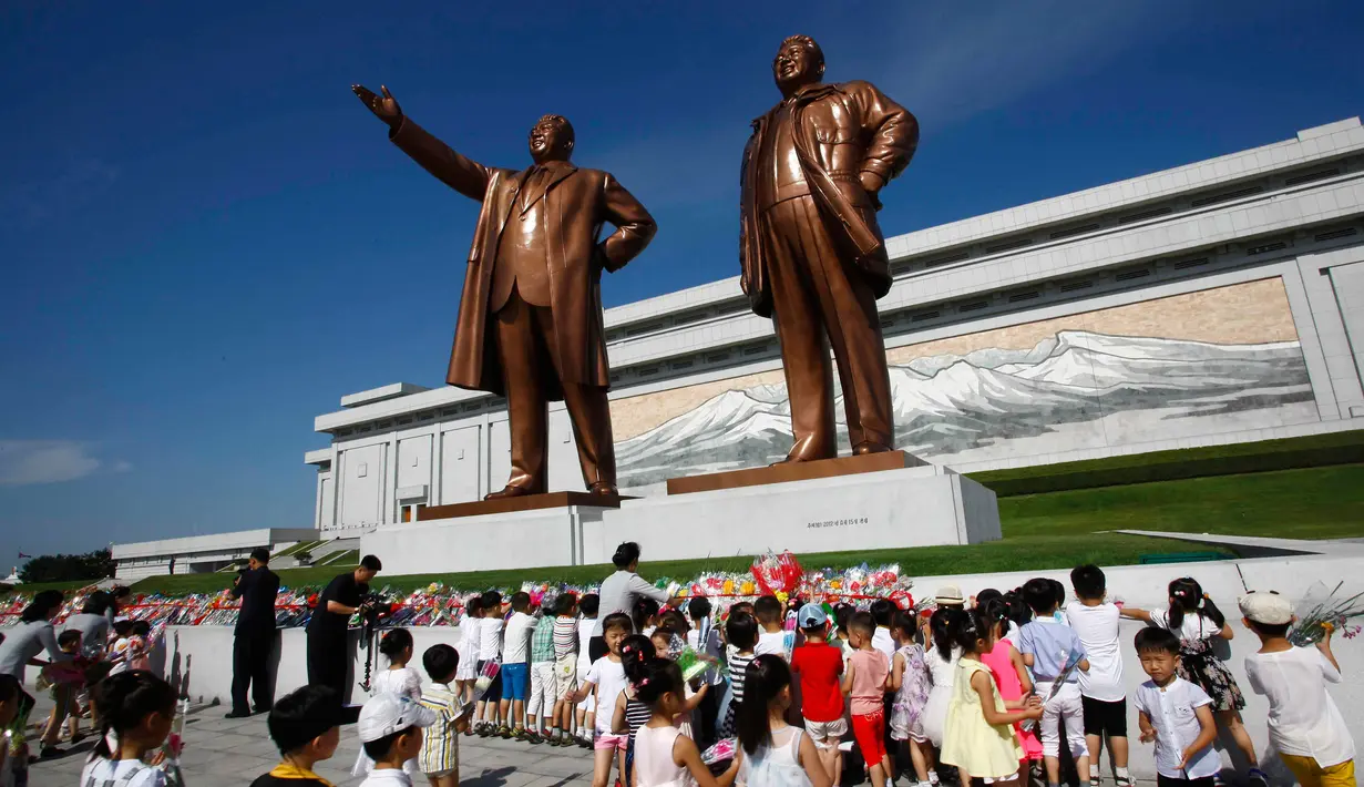 <p>Anak-anak menaruh bunga dekat patung mendiang pemimpin Kim Il Sung dan Kim Jong Il saat memperingati 25 tahun meninggalnya Kim Il Sung di Bukit Mansu, Pyongyang, Korea Utara, Senin (8/7/2019). (AP Photo/Jon Chol Jin)</p>