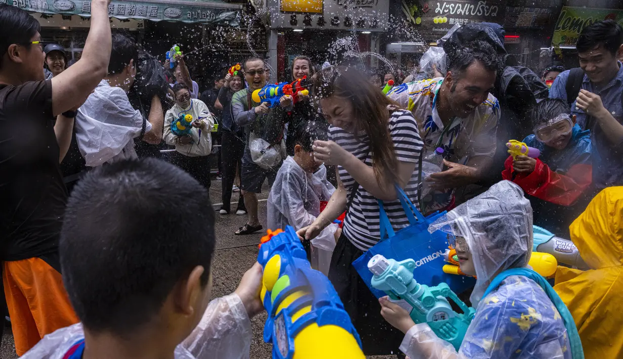 Para peserta menyatakan hujan tidak menghentikan rasa antusias mereka dan berharap untuk mendapatkan berkah dengan bergabung dalam perayaan Songkran setelah tiga tahun ditiadakan. (AP Photo/Louise Delmotte)