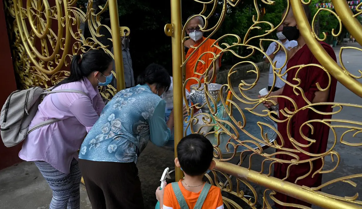 Warga memberikan makanan dan sedekah kepada biksu Buddha saat Festival Pchum Ben (Festival Kematian) di luar pagoda di Phnom Penh, Kamboja, 24 September 2021. Pihak berwenang menghentikan perayaan Festival Kematian karena pandemi COVID-19. (TANG CHHIN Sothy/AFP)