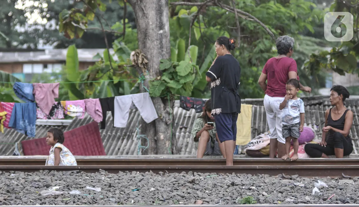 Sejumlah orang tua menyaksikan anak-anak bermain di dekat rel kereta api di kawasan Bahari Ujung, Tanjung Priok, Jakarta Utara, Selasa (24/5/2022). Minimnya fasilitas dan ruang terbuka hijau di kawasan tersebut menyebabkan anak-anak setempat memilih bermain di sekitar perlintasan kereta api yang dapat membahayakan keselamatan mereka. (merdeka.com/Iqbal S Nugroho)