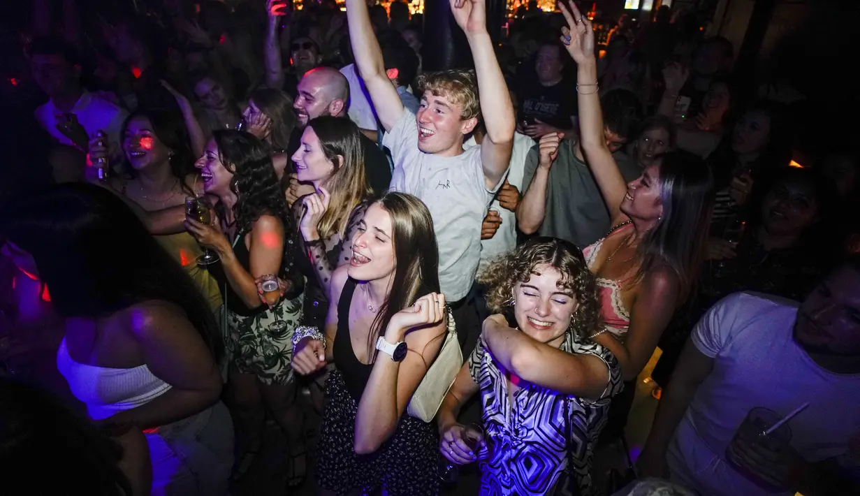 Orang-orang bereaksi di lantai dansa tak lama setelah pembukaan kembali, di The Piano Works di Farringdon, di London, Senin (19/7/2021). Kelab malam di negara itu dibuka kembali untuk pertama kalinya dalam 17 bulan karena hampir semua aturan virus corona dihapus. (AP Photo/Alberto Pezzali)