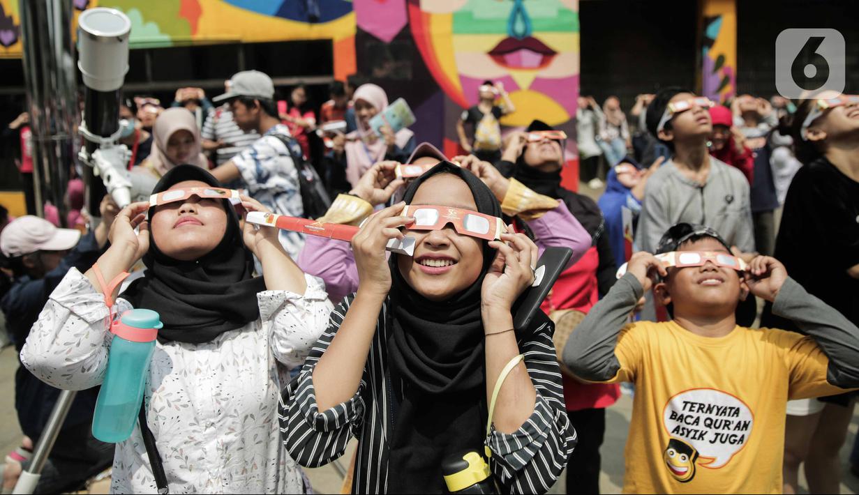 Pengunjung mengamati gerhana matahari cincin memakai kacamata khusus di Planetarium Taman Ismail Marzuki, Jakarta, Kamis (26/12/2019). Planetarium menyediakan sekitar 10 teleskop dan kacamata khusus agar pengunjung bisa menyaksikan gerhana matahari cincin dengan aman. (Liputan6.com/Faizal Fanani)