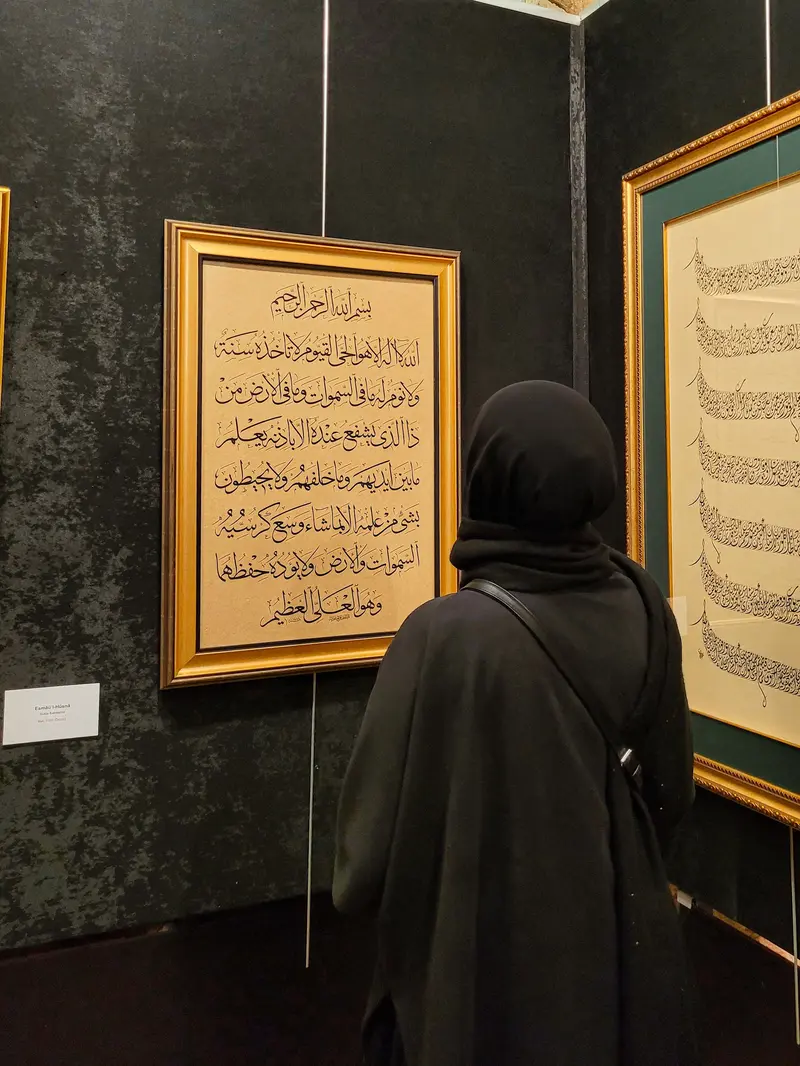 Wallpaper kaligrafi indah berupa muslim sedang membaca ayat suci Al-Qur'an di dinding