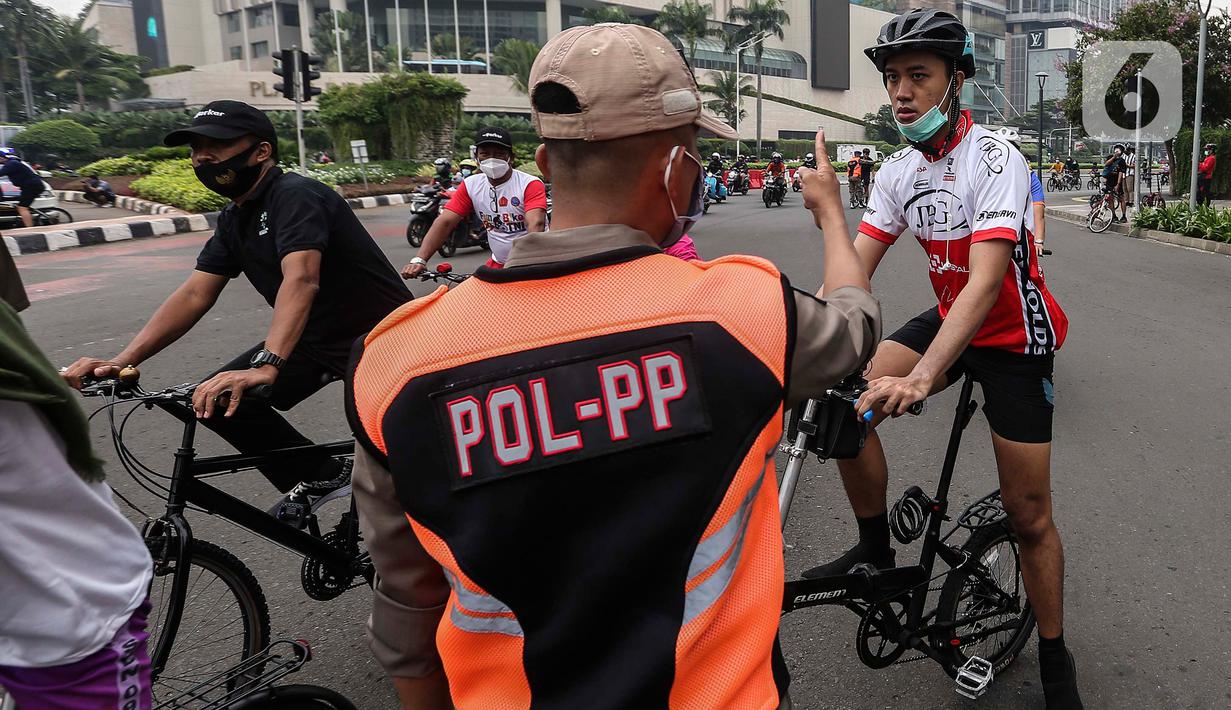 Satpol PP menegur warga yang berolahraga tidak mengenakan masker dengan benar di kawasan Bundaran HI, Jakarta, Minggu (17/1/2021). Sosialisasi penggunaan masker untuk mencegah penularan virus corona COVID-19 masih saja diabaikan karena rendahnya kesadaran masyarakat. (Liputan6.com/Johan Tallo)