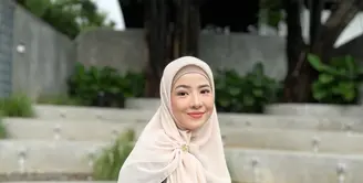 Ciptakan tampilan yang elegan dengan padu padan tiered dress warna gelap dan hijab warna cream cerah. [Foto: IG/natasharizkynew].