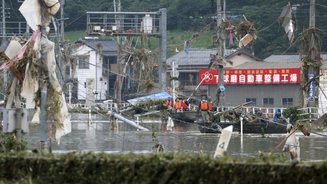 Anggota Japan Ground Self-Defense Force mengevakuasi warga ke tempat yang lebih aman menggunakan perahu di Desa Kuma, Prefektur Kumamoto, Jepang, Minggu (5/7/2020). Hujan deras memicu banjir dan tanah longsor di sejumlah wilayah Jepang. (Kyodo News via AP)