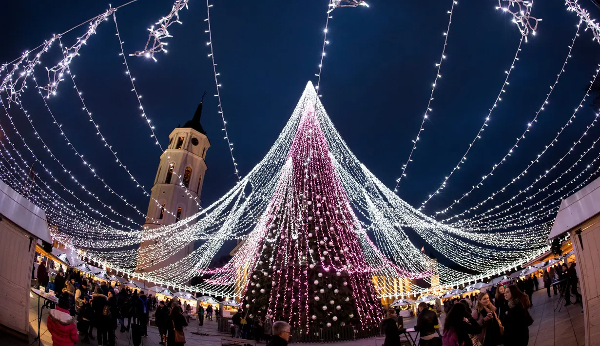 Orang-orang berjalan di sekitar pohon Natal raksasa yang berdiri di Alun-Alun Katedral di Vilnius, Lithuania, 5 Desember 2017. Karena keindahannya, pohon Natal tersebut menjadi salah satu pohon Natal terindah di dunia. (AP Photo/Mindaugas Kulbis)