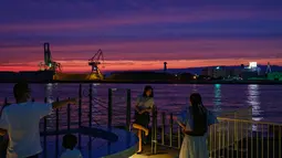 Seorang wanita berpose untuk foto di kawasan pejalan kaki pelabuhan di Osaka (20/9/2020). Pelabuhan Osaka juga memiliki mitra kembar dengan Pelabuhan Busan. (AFP/Philip Fong)