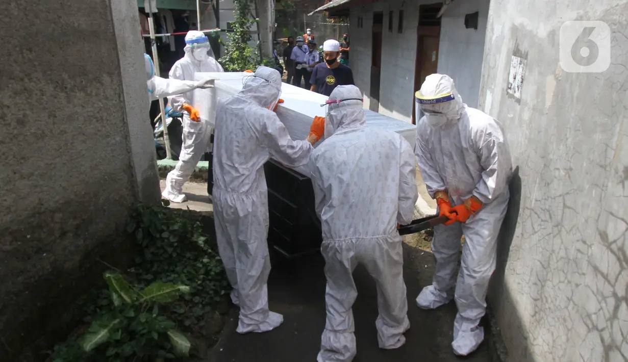 Petugas pemulasaraan jenazah Covid-19 memasukan peti jenazah yang meninggal ketika menjalani isolasi mandiri ke ambulans di Kampung Gedong, Jakarta, Sabtu (10/7/2021). Proses pemulasaran jenazah dilakukan sesuai prokes Covid-19 dikarenakan hasil test swab korban positif. (merdeka.com/Imam Buhori)