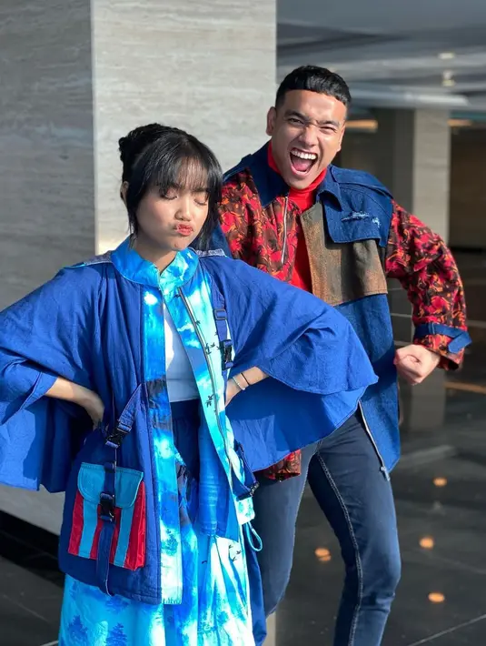 Fuji tampil mengenakan innerwear putih polos dan outerwear berlengan kimono dengan detail kantong dan zip di bagian tengah. Sedangkan Fadly mengenakan innerwear turtleneck merah polos, dengan outerwear bernuansa merah berdetail kantong dan zip. Foto: Instagram.