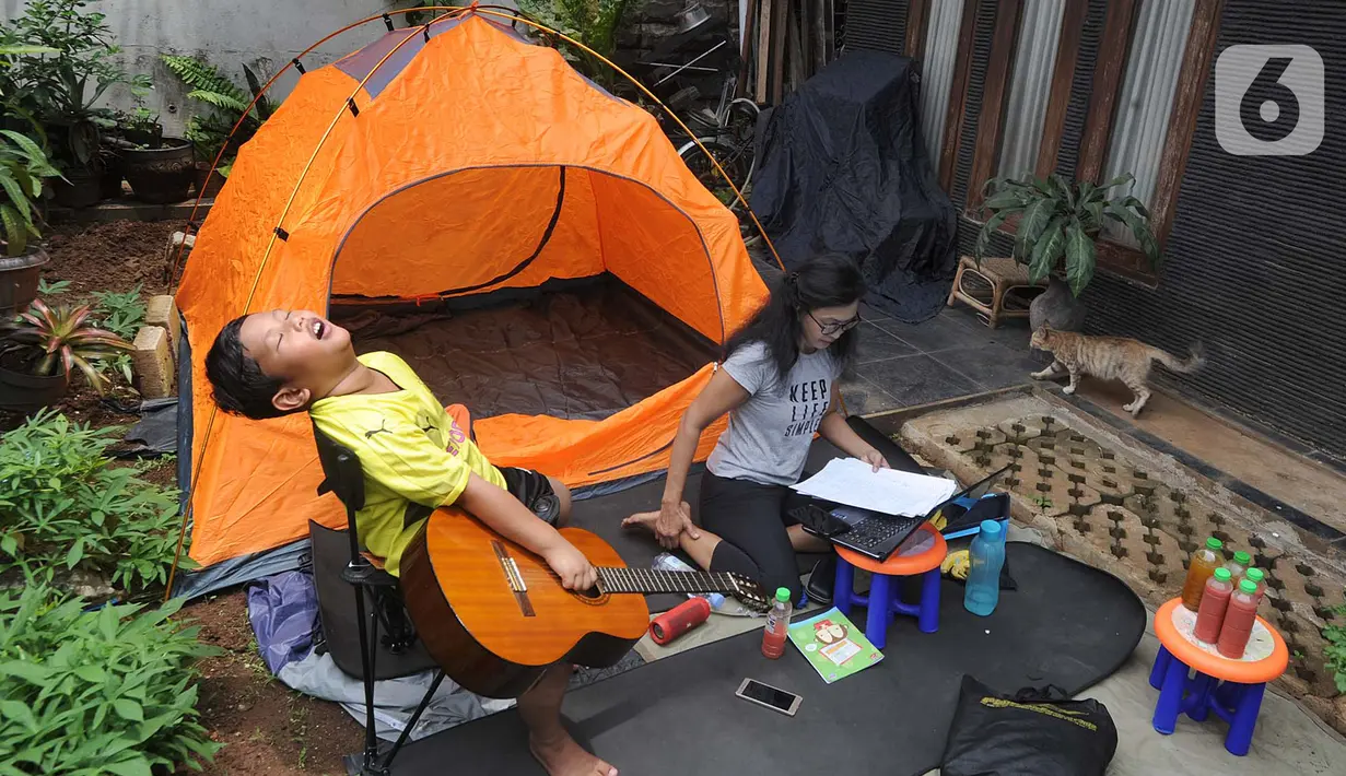 Aktivitas warga saat work from home di halaman rumahnya di kawasan Cinere, Depok, Senin (23/3/2020). Imbauan pemerintah untuk bekerja dari rumah atau work from home untuk mencegah penularan virus corona, dimanfaatkan warga dengan beragam aktivitas. (merdeka.com/Arie Basuki)