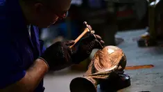 Pekerja menggunakan palu dan pahat membuat ukiran replika trofi Piala Dunia FIFA di piala Italia dan pabrikan medali GDE Bertoni di Paderno Dugnano, Milan (11/4). Piala Dunia akan diselenggarakan 14 Juni sampai 15 Juli di Rusia. (AFP Photo/Miguel Medina)