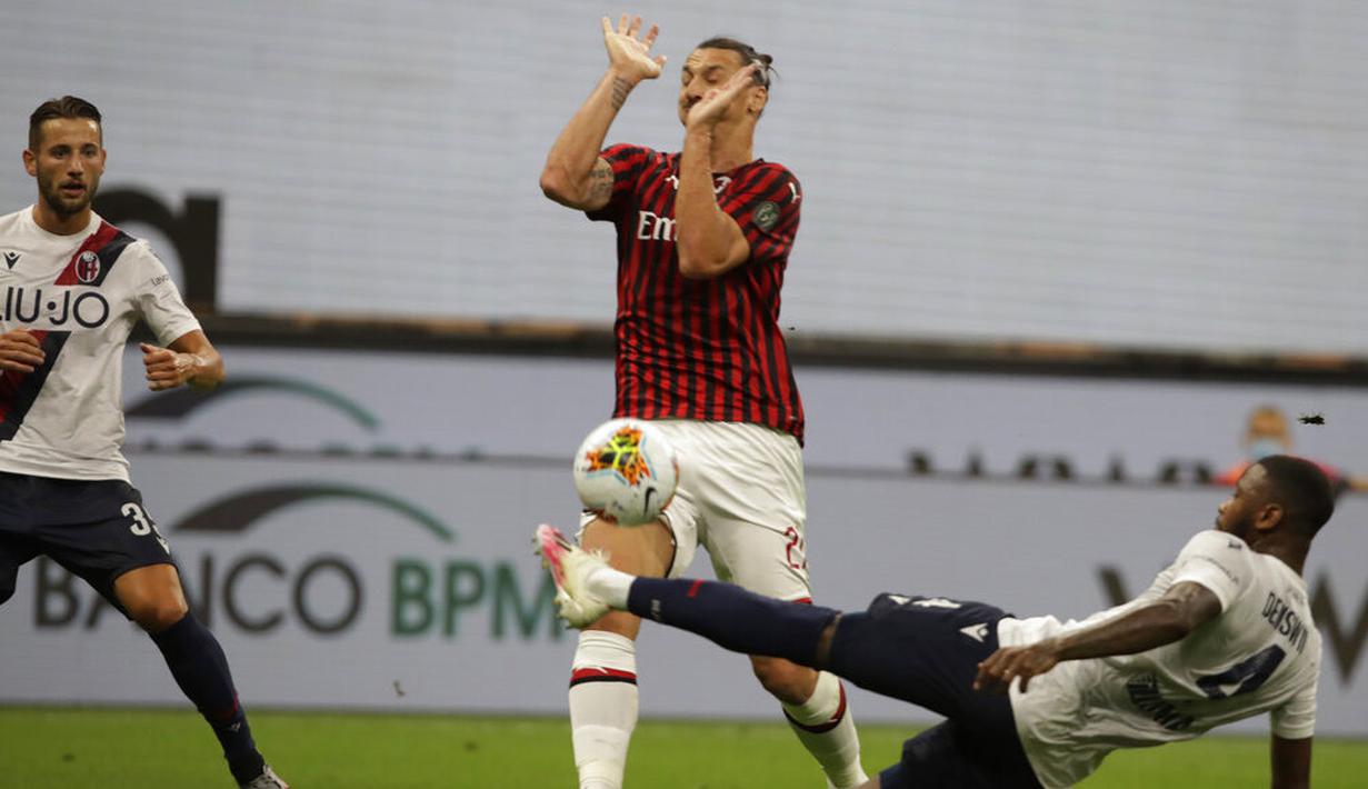 Striker AC Milan, Zlatan Ibrahimovic, dihadang oleh pemain Bologna, Stefano Denswil, pada laga Serie A di Stadion San Siro, Sabtu (18/7/2020). AC Milan menang dengan 5-1 atas Bologna. (AP/Luca Bruno)